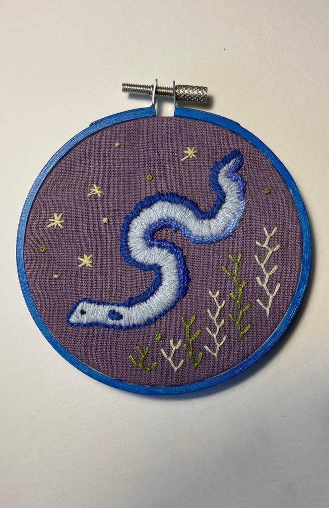 an embroidery of a European eel on hand-dyed purple fabric