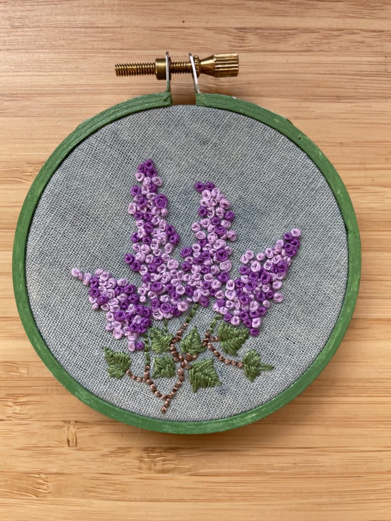 an embroidery of a bouquet of lilacs on indigo fabric