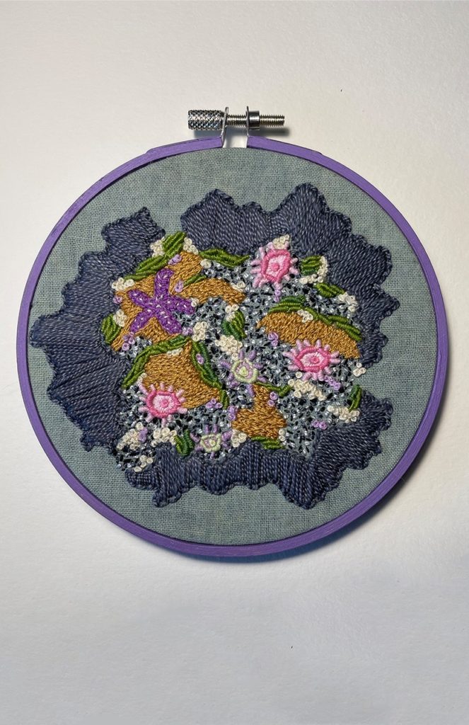 an embroidery of a tide pool on indigo fabric